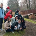 Grupa młodzieży z opiekunem na tle mostku w ogrodzie botanicznym.
