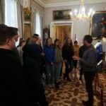 Uczniowie klasy II B podczas ziwedzania Pałacu w Wilanowie. Rozmawiają z przewodnikiem w czasie lekcji muzealnej. w tle ekspnaty i obrazy muzealne